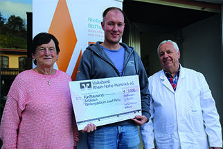 Fabian Korb hält einen symbolischen Scheck über 5.000 Euro zugunsten der Stfean-Morsch-Stiftung. Neben ihm stehen links Helga Peitz und rechts Weinlaborant Josef Peitz.