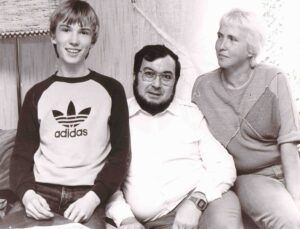 Das Schwarzweißfoto zeigt den jugendlichen Stefan Morsch, der auf einem Sofa lächelnd neben seinem Vater Emil und seiner Mutter Hiltrud sitzt.