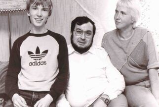 Das Schwarzweißfoto zeigt den jugendlichen Stefan Morsch, der auf einem Sofa lächelnd neben seinem Vater Emil und seiner Mutter Hiltrud sitzt.