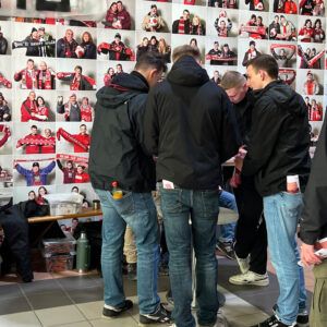 Eine Gruppe junger Männer füllt die Einwilligungserklärung an einem Stehtisch aus