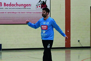 Ein Mann in Sportkleidung geht über ein Handballspielfeld.