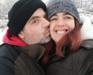 Stammzellspender Chris Albrecht küsst seine Frau in einer Schneelandschaft.